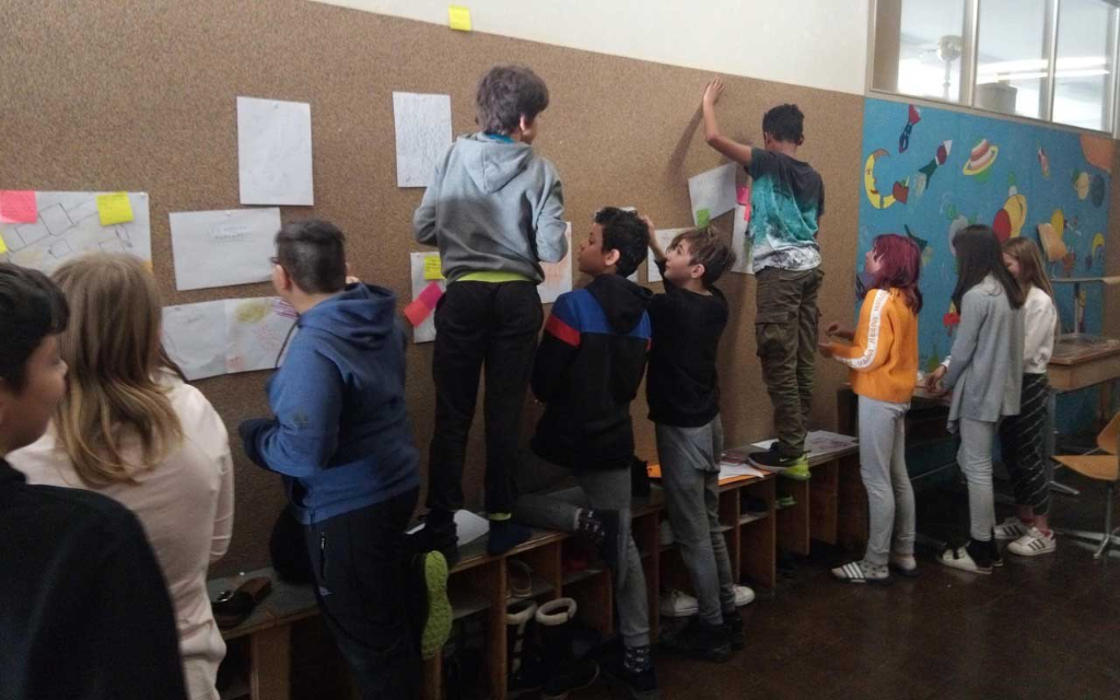 Les élèves épinglent leurs idées sur un mur.