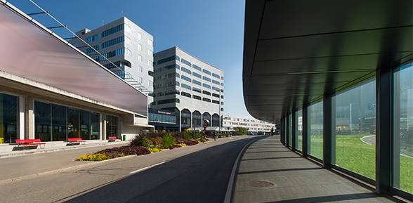 Das Bild zeigt das Operation Center 1 am Flughafen Zürich-Kloten, den Hauptsitz der MeteoSchweiz. Es ist ein 9-stöckiges Gebäude mit grossen Glasfronten.