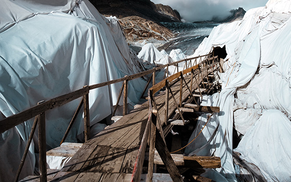 Bild des Rhonegletschers, der mit Tüchern abgedeckt und durch eine Brücke zugänglich gemacht ist.