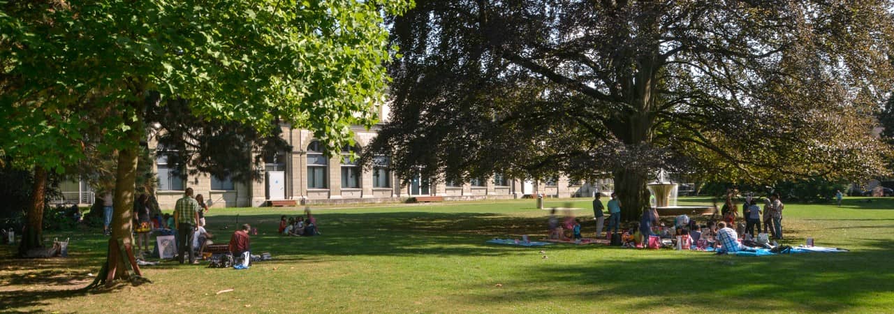 Persone sedute sotto gli alberi nel parco nella città di Baden.